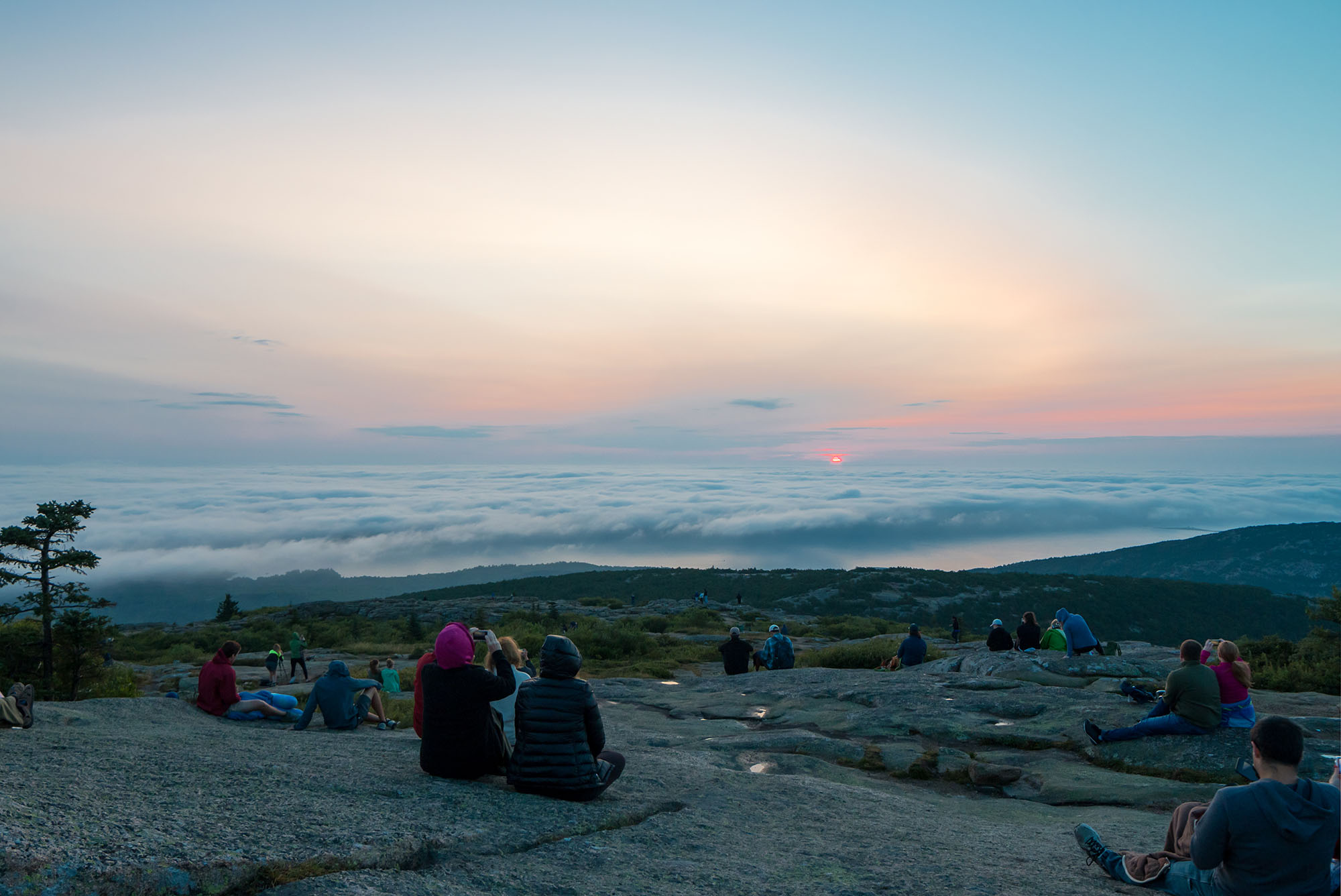 Photo of people sitting at top of Cadillac Mountain, Acadia National Park, waiting waiting to take pictures at sunrise.
