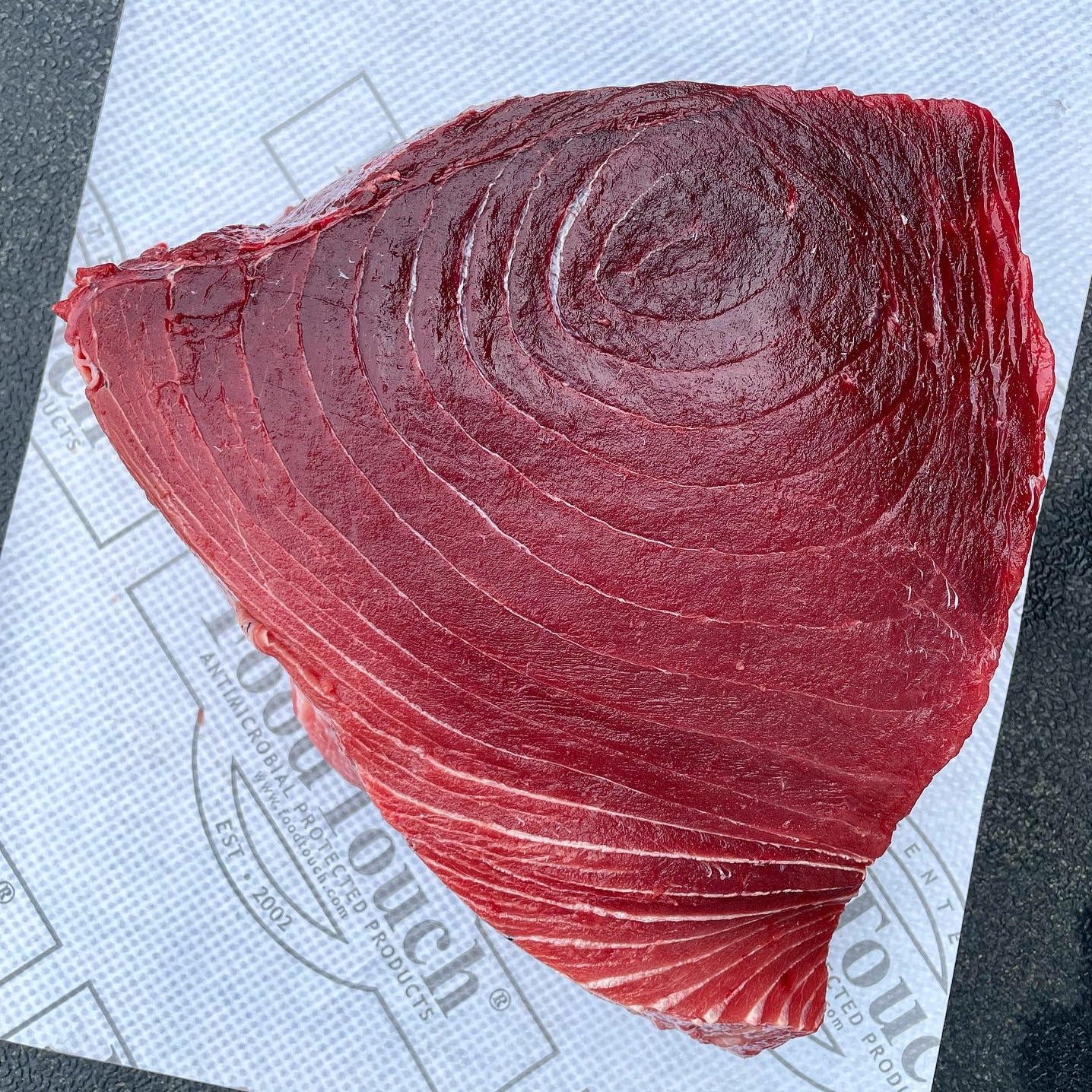 A piece of raw tuna on a white surface.