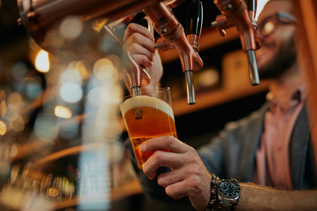 Bartender pouring a craft beer from copper taps